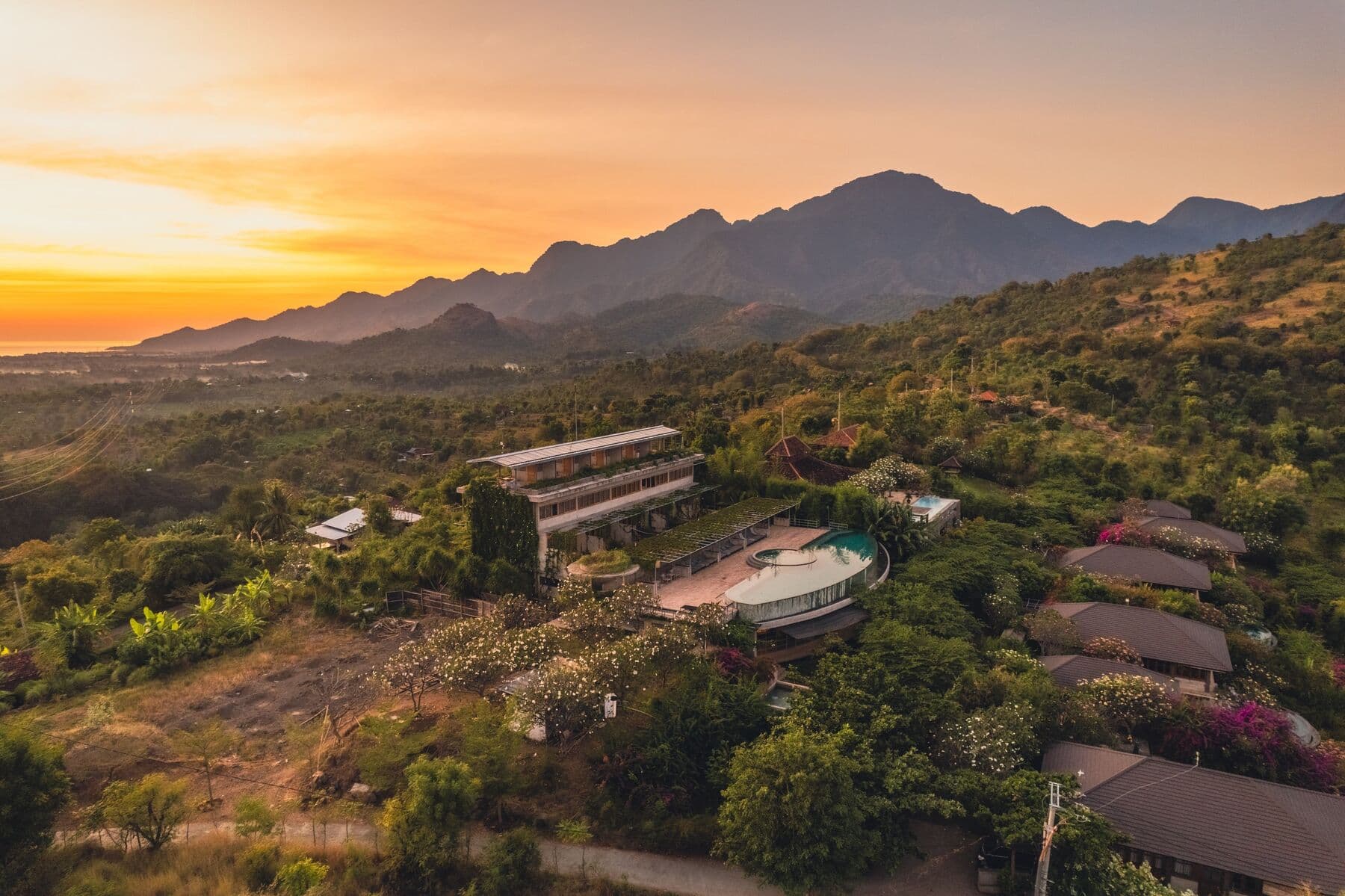 Aerial view of Sumberkima Hill at sunset, with mountains behind