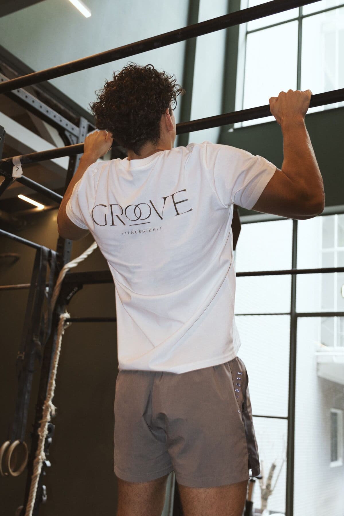 A man in a Groove T-shirt doing a pull-up on a bar