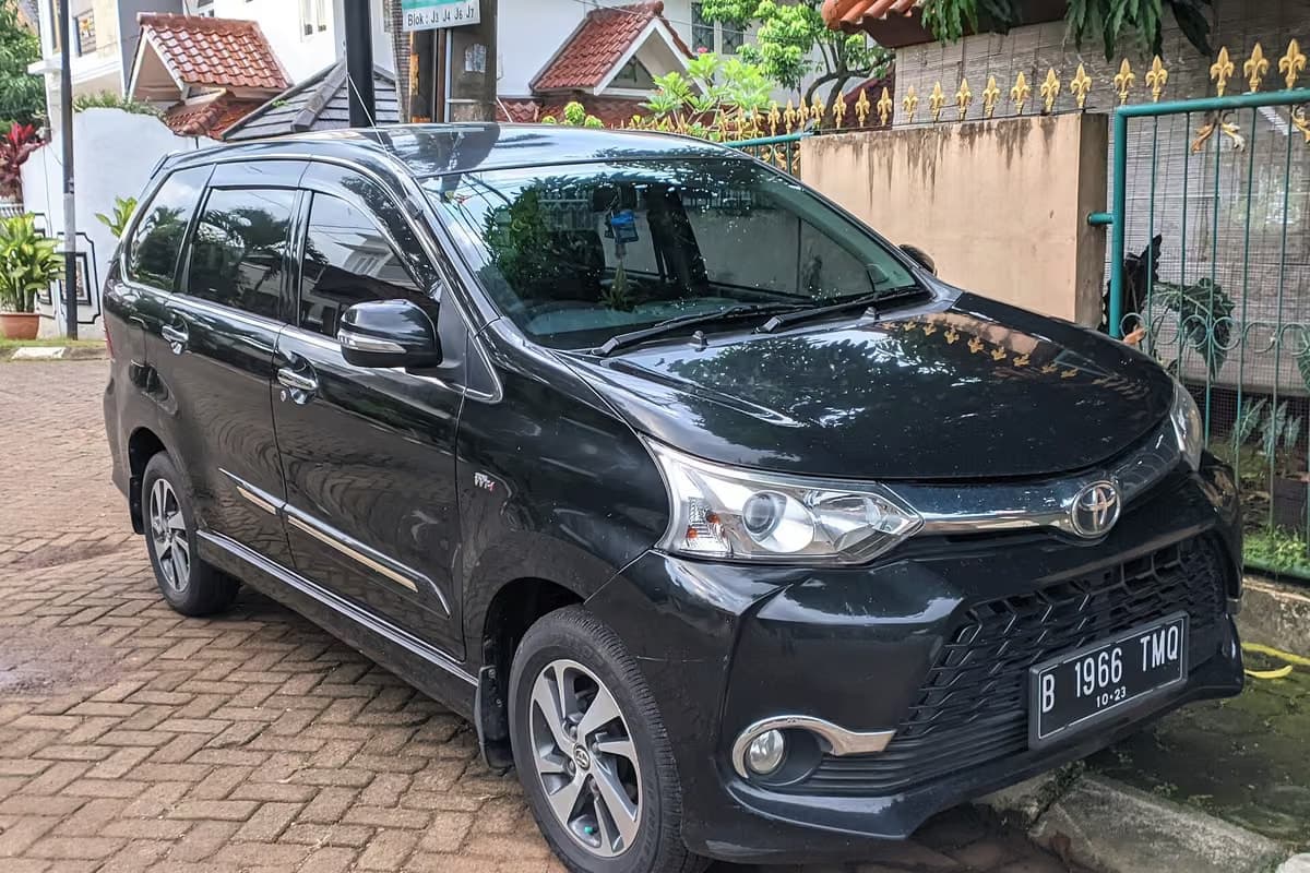 A black Toyota Avanza people carrier parked on a street in Indonesia
