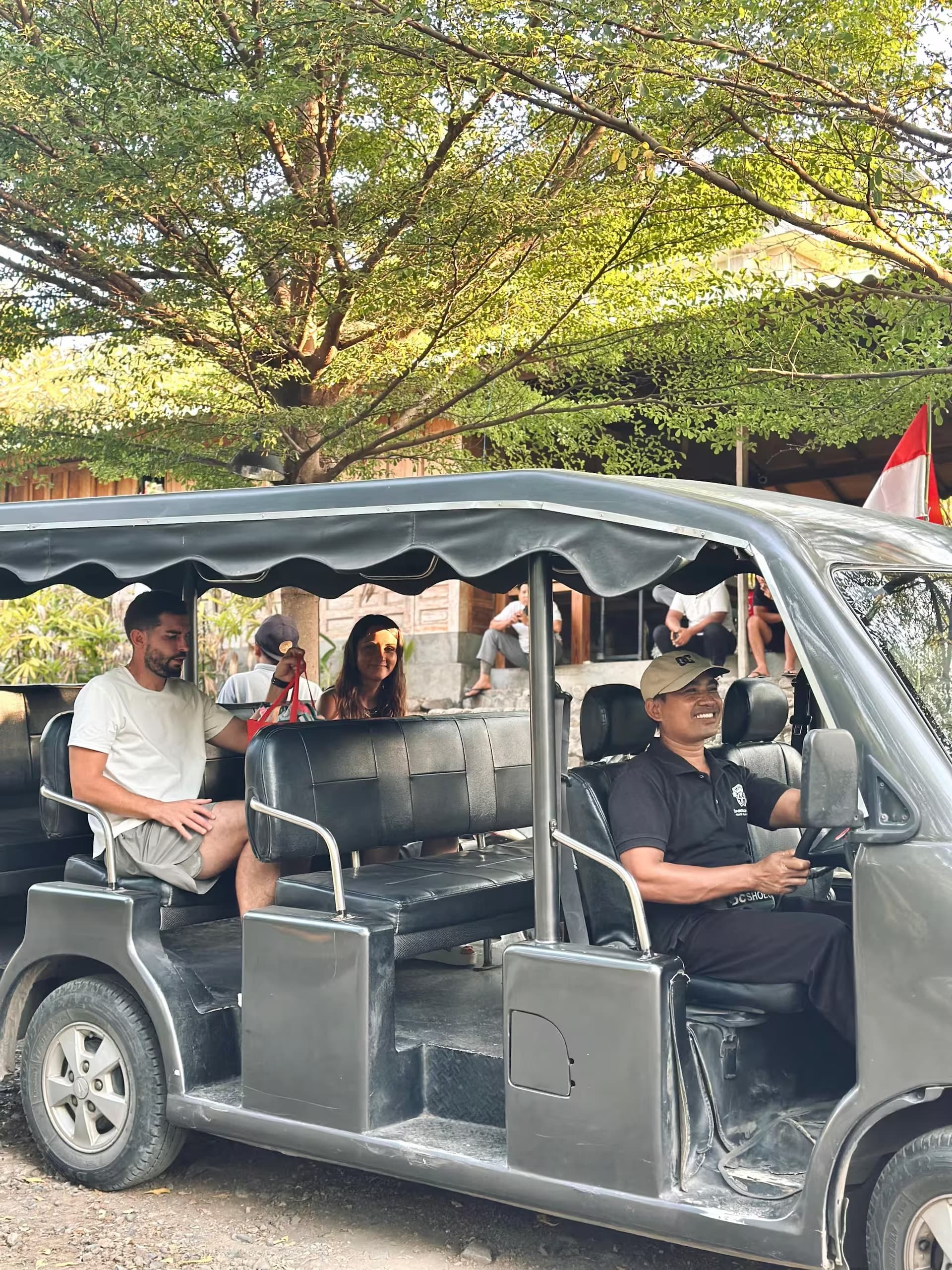 Guests riding the open-sided Sumberkima Hill shuttle with the driver