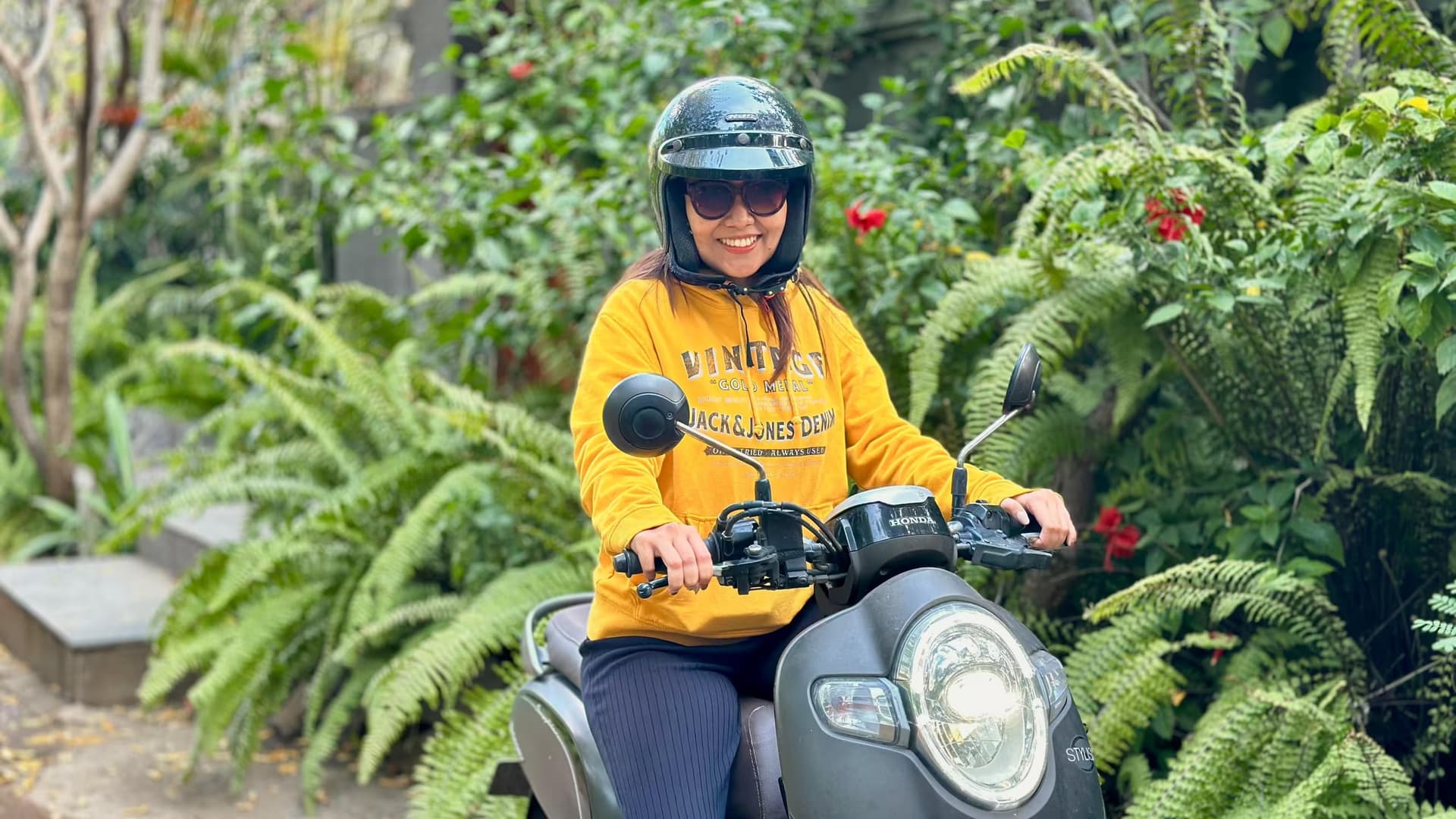 A guest wearing a helmet on a rental scooter at Sumberkima Hill