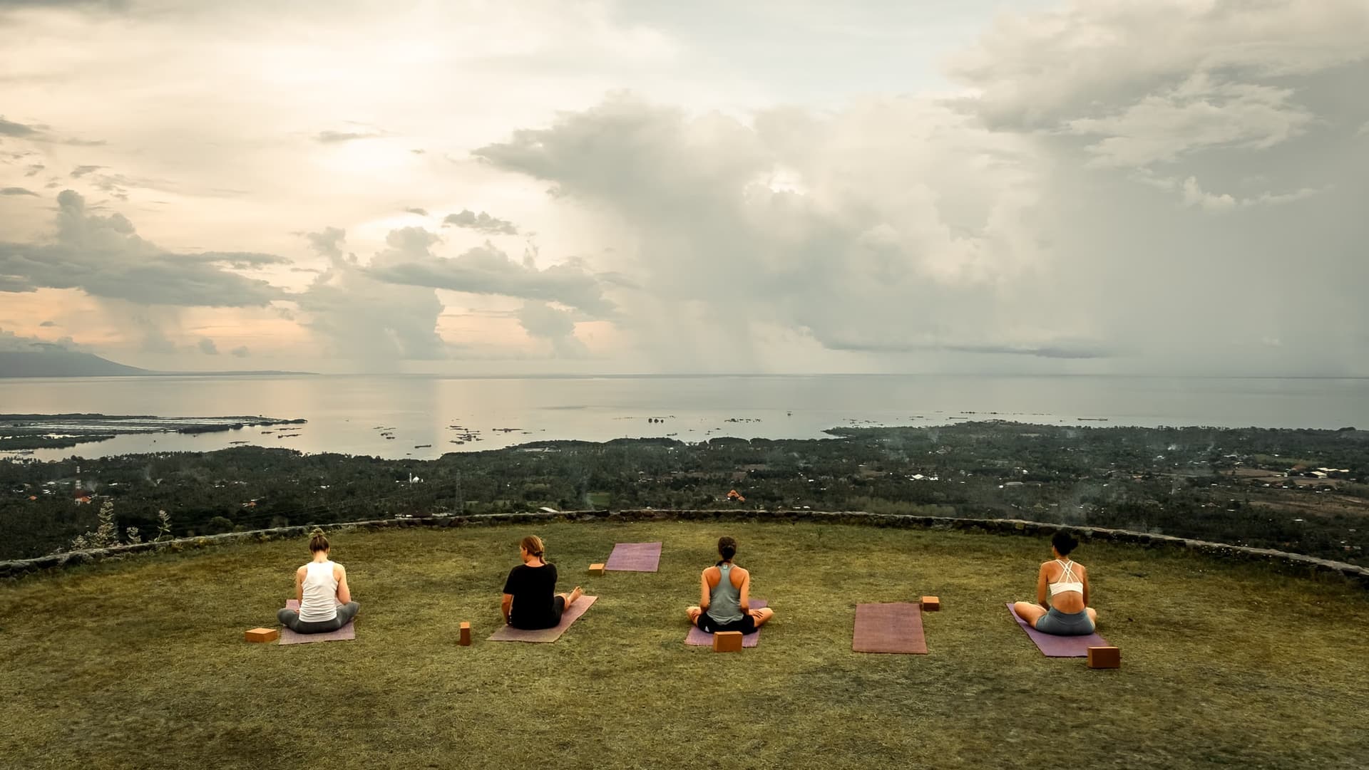 Yoga practitioners at Sumberkima Stage with mountain backdrop