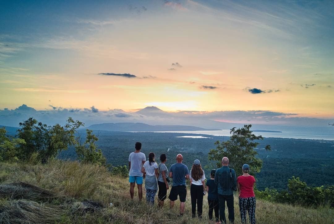 Guests hiking from Sumberkima Hill with sunset views over the bay and volcanoes