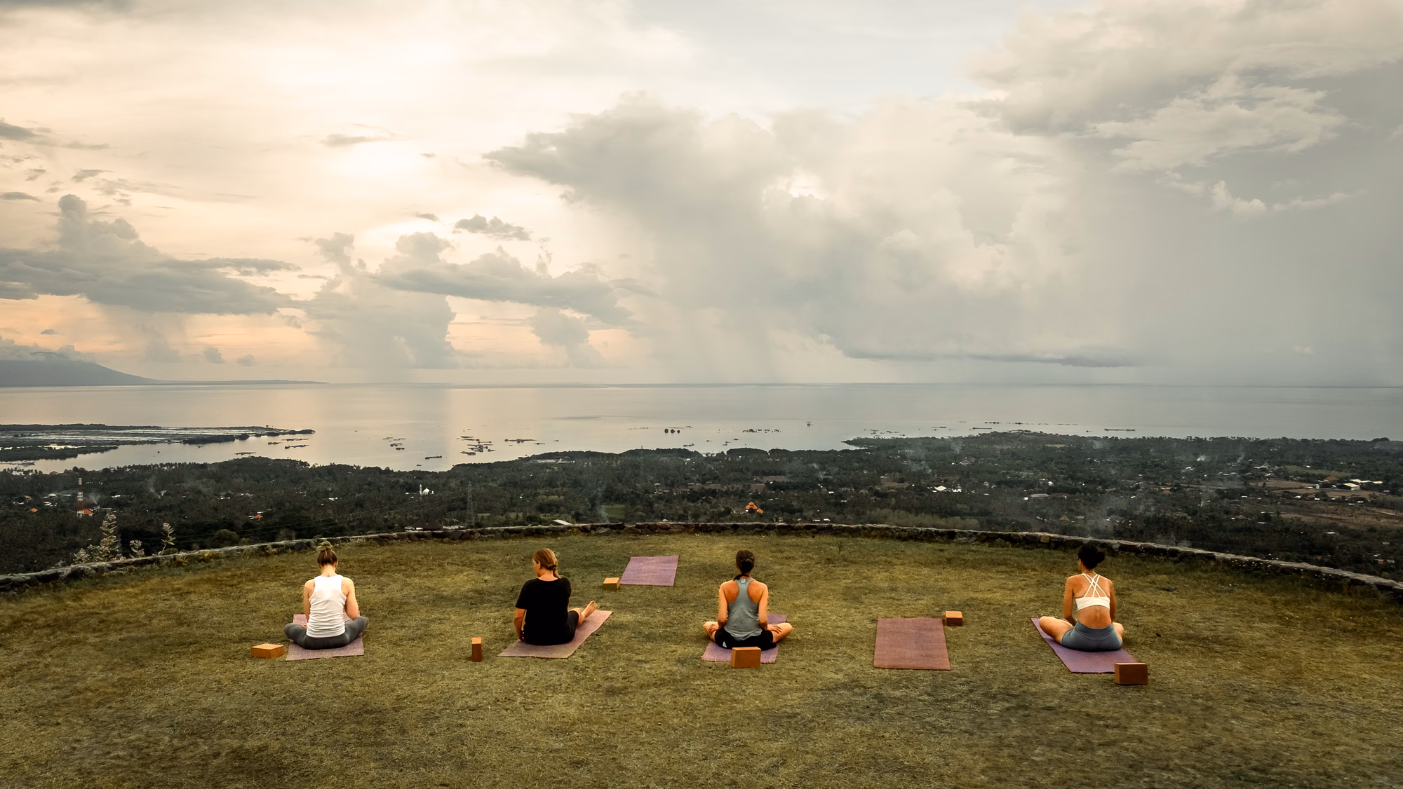 Yoga practitioners at Sumberkima Stage with mountain backdrop