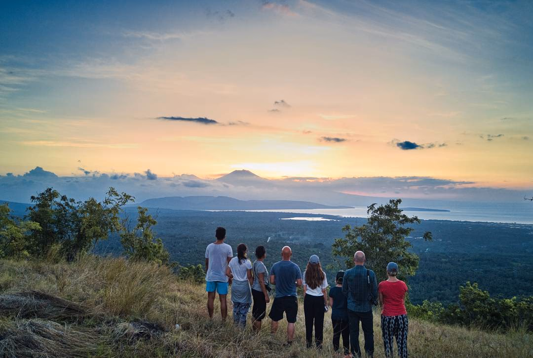 Guests hiking from Sumberkima Hill with sunset views over the bay and volcanoes